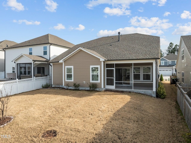 rear view of house featuring a lawn, roof with shingles, a fenced backyard, and a sunroom