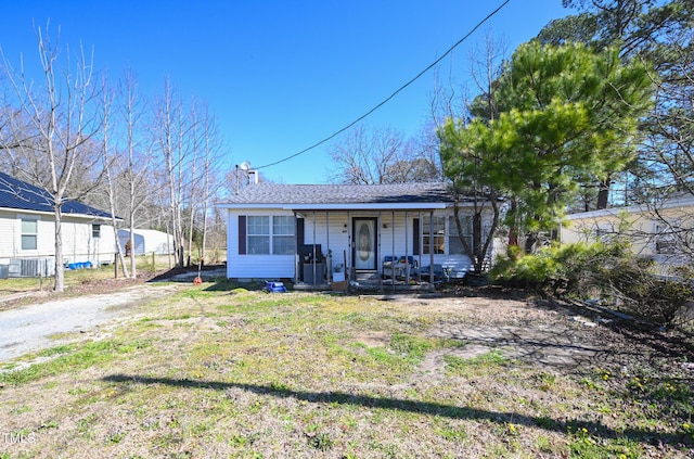 view of front of home featuring central air condition unit, roof with shingles, covered porch, and a front yard