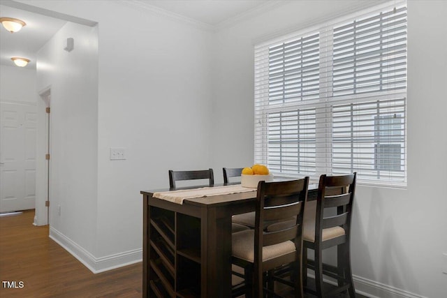 dining room with baseboards, ornamental molding, and dark wood finished floors