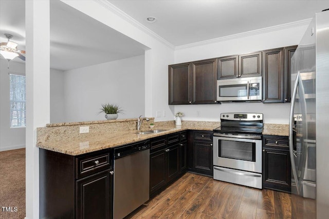 kitchen featuring ornamental molding, light stone counters, a peninsula, stainless steel appliances, and a sink