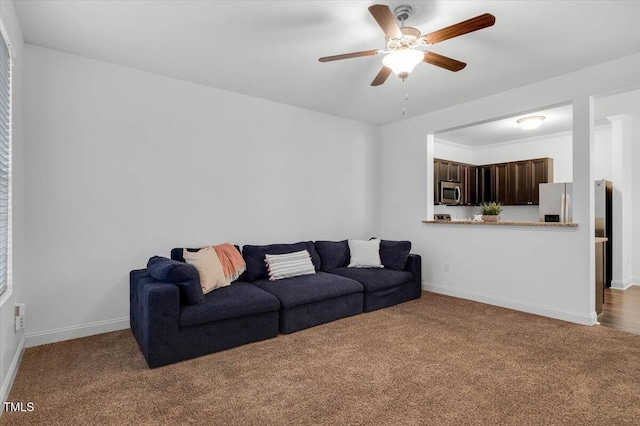 carpeted living area featuring baseboards and ceiling fan