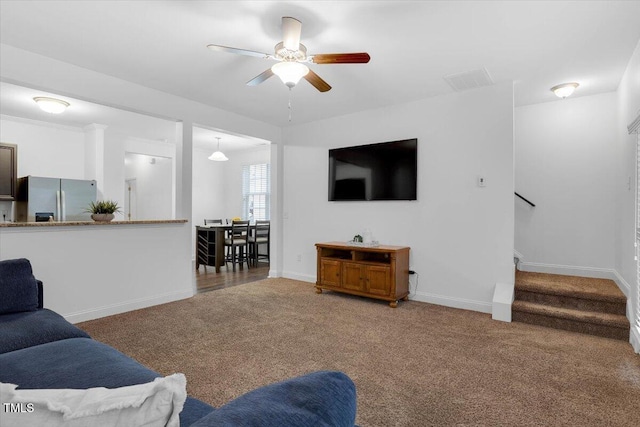 living room with stairs, carpet, baseboards, and ceiling fan