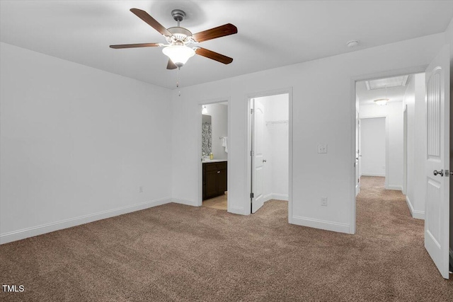 unfurnished bedroom featuring a spacious closet, baseboards, light colored carpet, attic access, and a closet