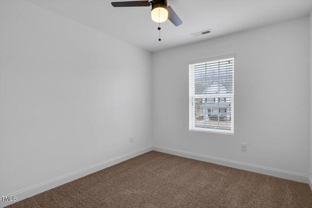 empty room featuring visible vents, a ceiling fan, baseboards, and dark colored carpet