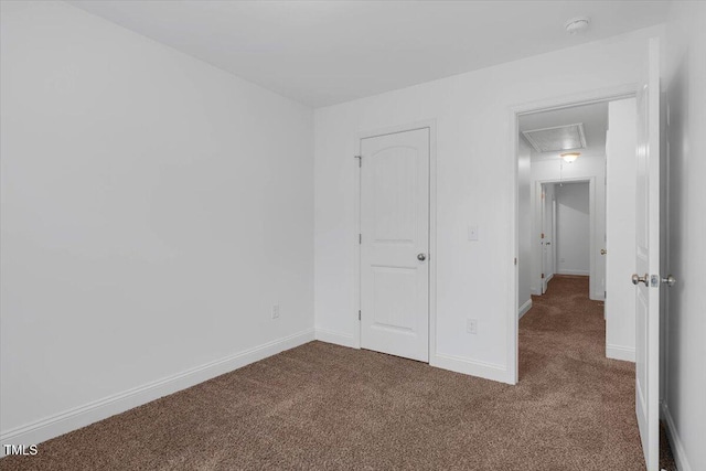 unfurnished bedroom featuring attic access, carpet flooring, and baseboards