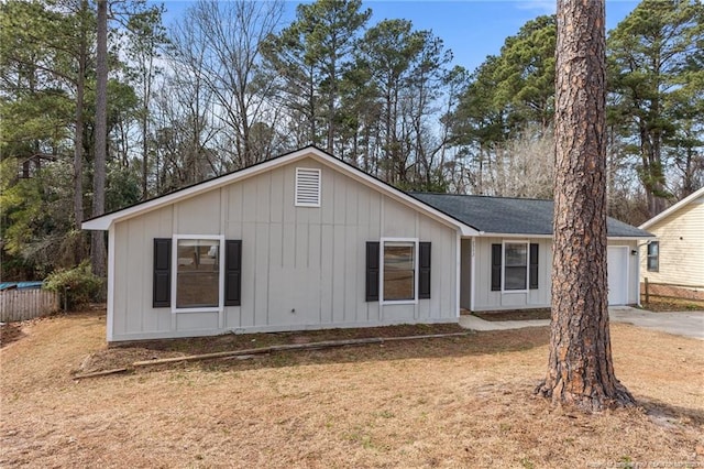 rear view of house featuring a garage, a lawn, board and batten siding, and driveway