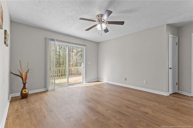 spare room with ceiling fan, baseboards, a textured ceiling, and wood finished floors