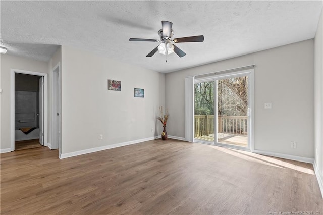 unfurnished room with ceiling fan, wood finished floors, baseboards, and a textured ceiling