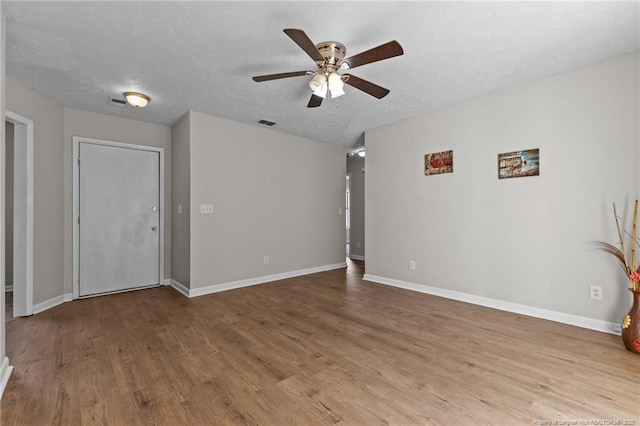 spare room with a textured ceiling, baseboards, and wood finished floors