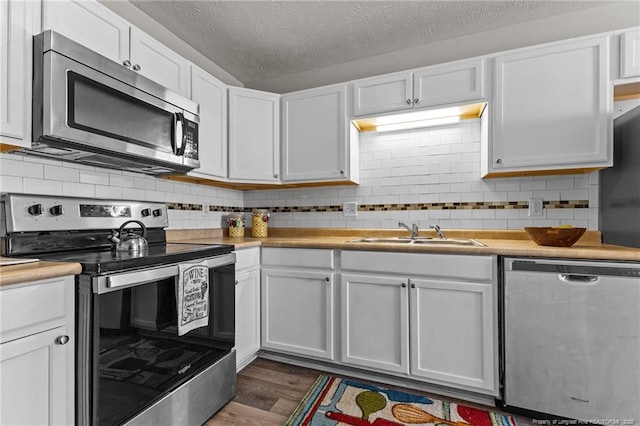 kitchen featuring a sink, dark wood-type flooring, appliances with stainless steel finishes, and white cabinets