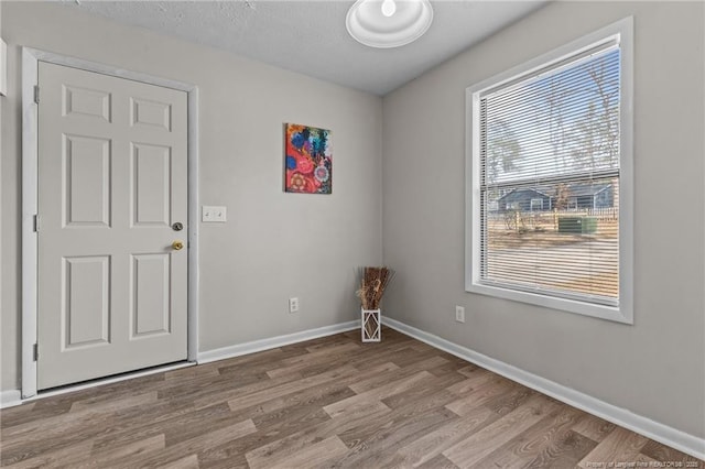 spare room with a textured ceiling, baseboards, and wood finished floors