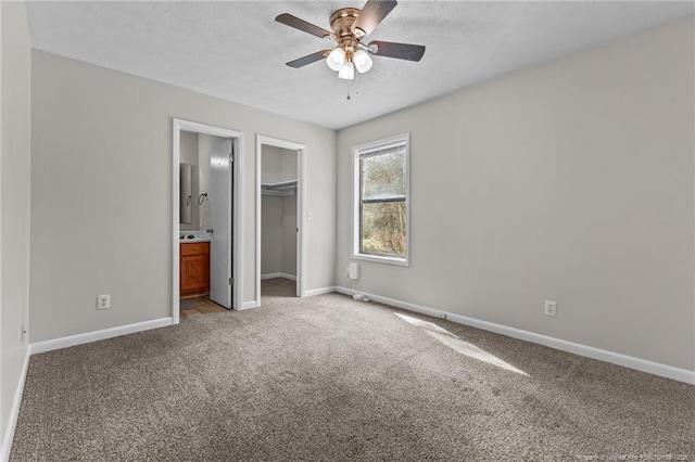 unfurnished bedroom featuring a walk in closet, connected bathroom, carpet floors, a closet, and baseboards