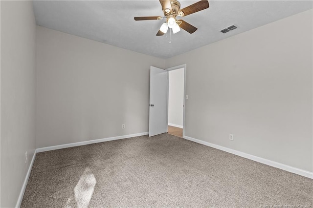 carpeted empty room with visible vents, baseboards, and a ceiling fan