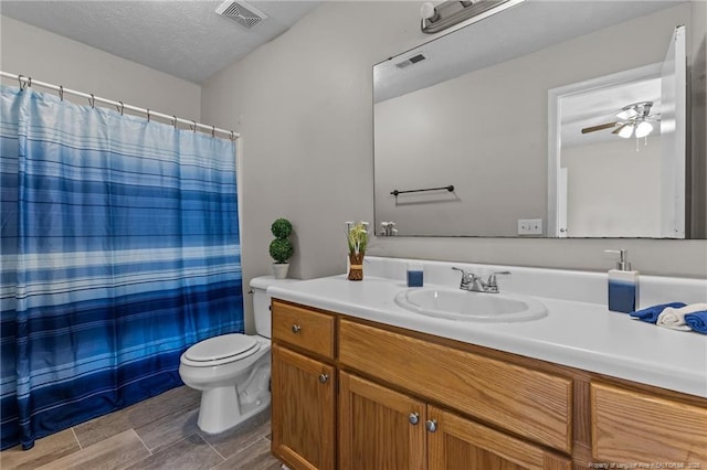 bathroom with vanity, toilet, visible vents, and a textured ceiling