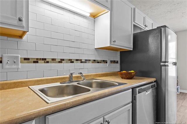 kitchen with tasteful backsplash, dishwasher, light countertops, a textured ceiling, and a sink