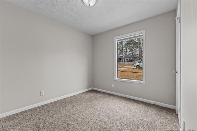 carpeted empty room featuring baseboards and a textured ceiling