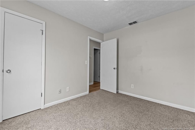 unfurnished bedroom with baseboards, carpet, visible vents, and a textured ceiling