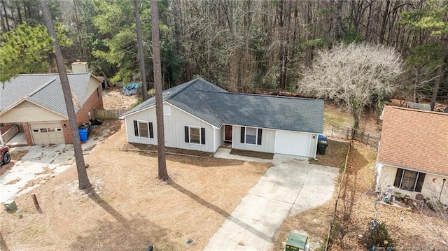 single story home featuring a garage, concrete driveway, roof with shingles, and fence