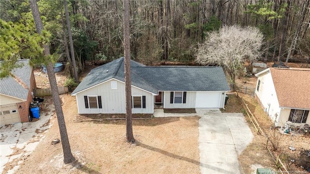 ranch-style home with fence, board and batten siding, roof with shingles, concrete driveway, and a garage