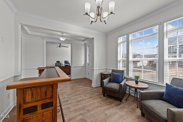 sitting room featuring a notable chandelier, baseboards, light wood-style floors, and crown molding