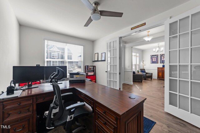 office space featuring wood finished floors and ceiling fan with notable chandelier