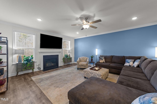 living area featuring a fireplace with flush hearth, baseboards, wood-type flooring, and ornamental molding