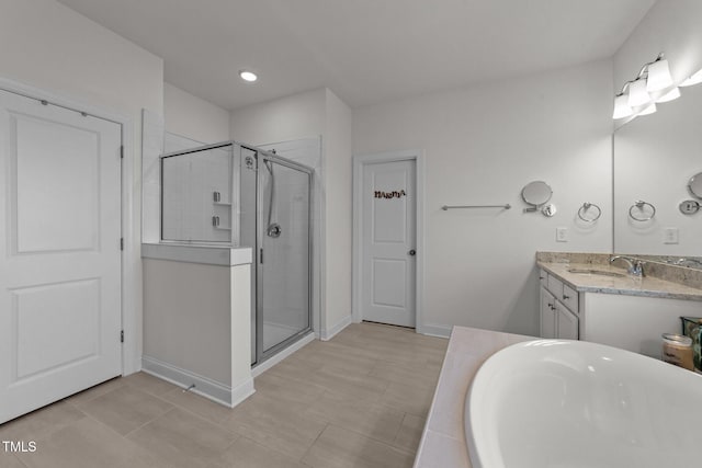 bathroom with a bathing tub, a stall shower, vanity, and baseboards