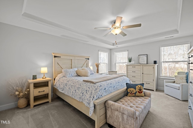 bedroom with a raised ceiling, light colored carpet, and baseboards