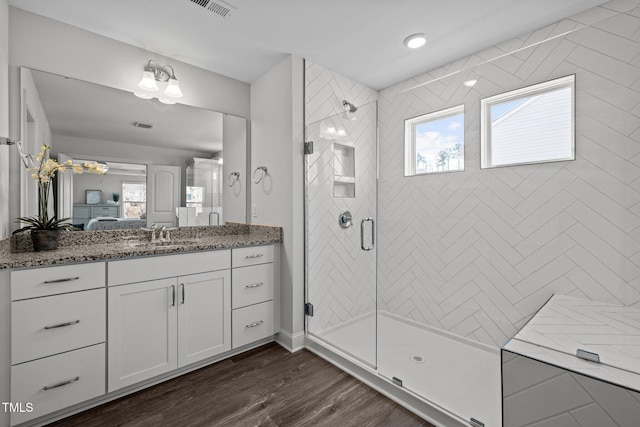 ensuite bathroom with a stall shower, a healthy amount of sunlight, wood finished floors, and ensuite bathroom