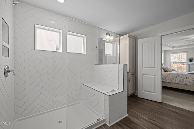 ensuite bathroom featuring a tile shower, ensuite bath, and wood finished floors