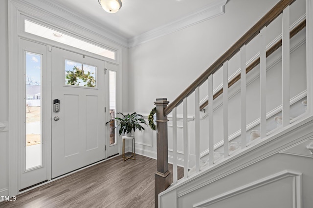 foyer entrance with a wainscoted wall, wood finished floors, and ornamental molding