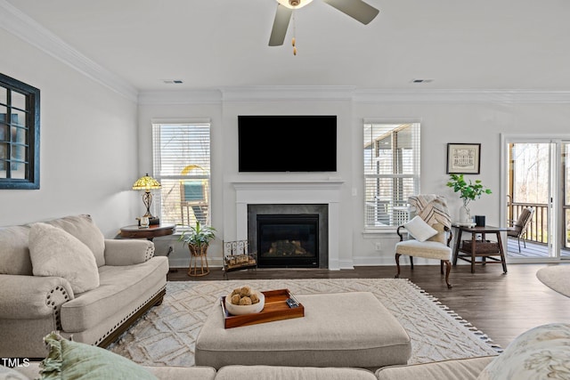 living area with wood finished floors, a healthy amount of sunlight, and ornamental molding