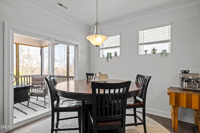 dining room with crown molding, wood finished floors, visible vents, and baseboards