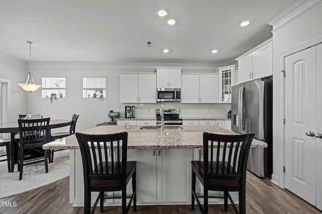 kitchen with a sink, stainless steel appliances, glass insert cabinets, and ornamental molding