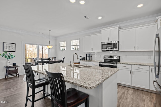 kitchen with a sink, crown molding, visible vents, and stainless steel appliances