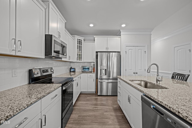 kitchen with ornamental molding, stainless steel appliances, dark wood-style floors, white cabinetry, and a sink