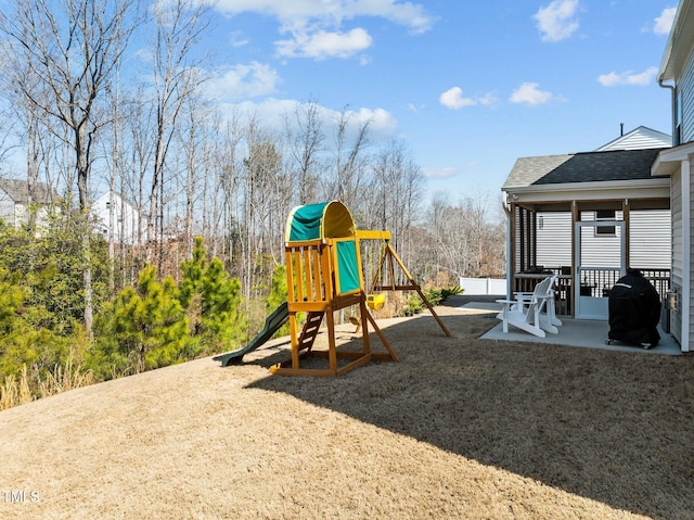 view of playground featuring a lawn and a patio area