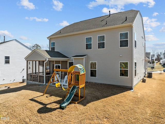 back of property with central AC and a shingled roof