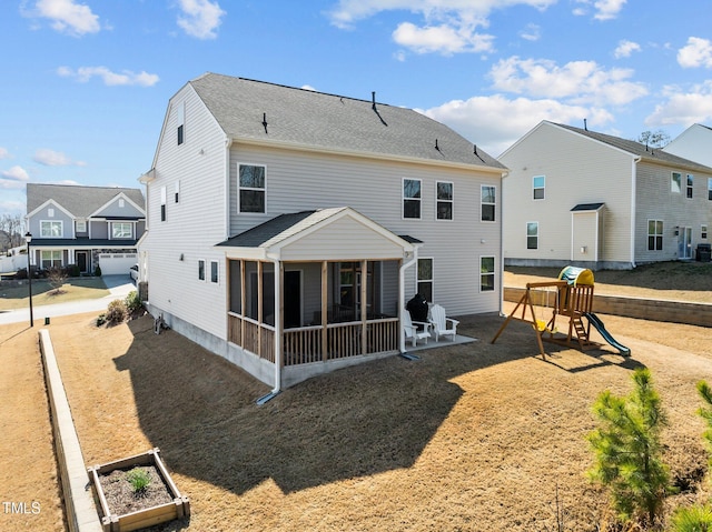 back of property featuring a playground, a vegetable garden, and a sunroom