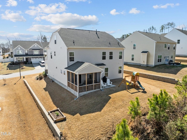 rear view of property with a residential view, a playground, and a sunroom