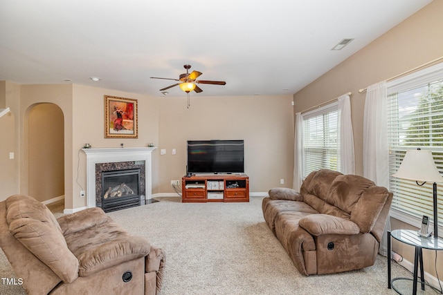 living area featuring visible vents, a high end fireplace, arched walkways, carpet, and baseboards