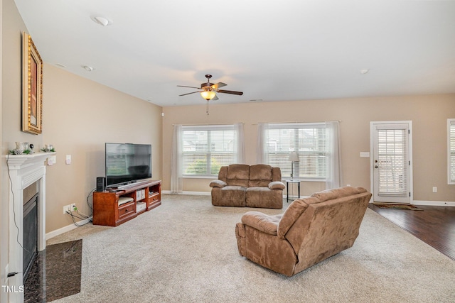 carpeted living room with a premium fireplace, baseboards, and a ceiling fan