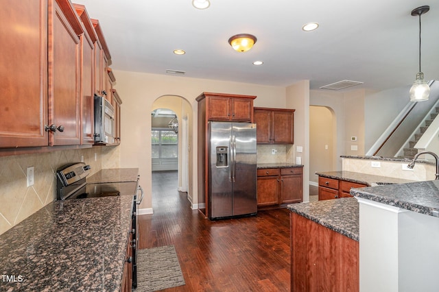 kitchen with arched walkways, dark wood-style floors, stainless steel appliances, and visible vents