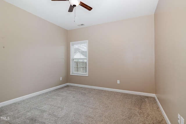 carpeted spare room with visible vents, baseboards, and a ceiling fan