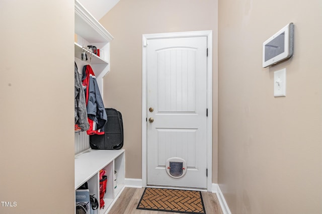 mudroom with light wood-style flooring, baseboards, and vaulted ceiling