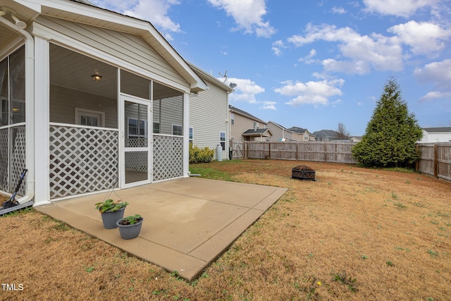 view of yard with a patio area, a fenced backyard, a sunroom, and a fire pit