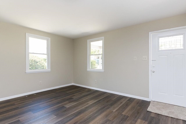 foyer entrance with dark wood-style floors, plenty of natural light, baseboards, and visible vents