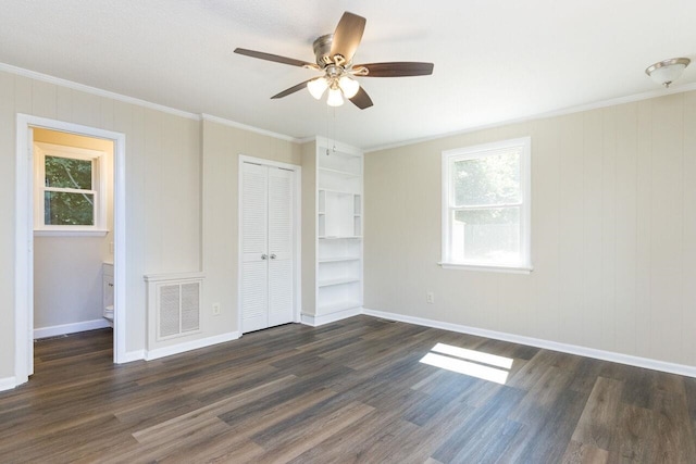 unfurnished bedroom with crown molding, dark wood-style floors, visible vents, and a closet