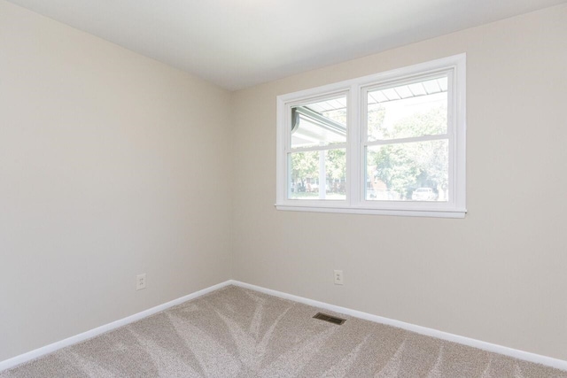 carpeted empty room featuring visible vents and baseboards