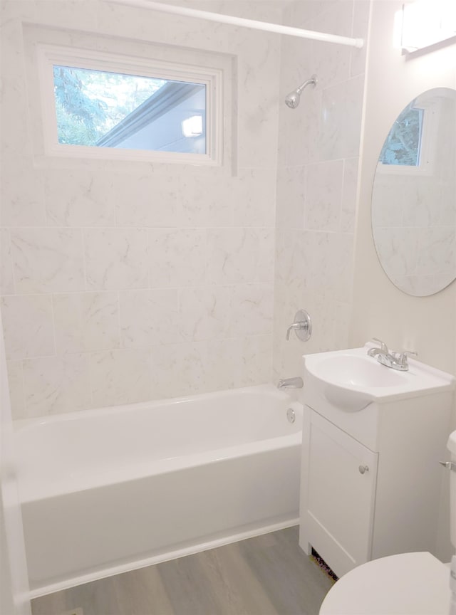 bathroom with toilet, washtub / shower combination, vanity, and wood finished floors